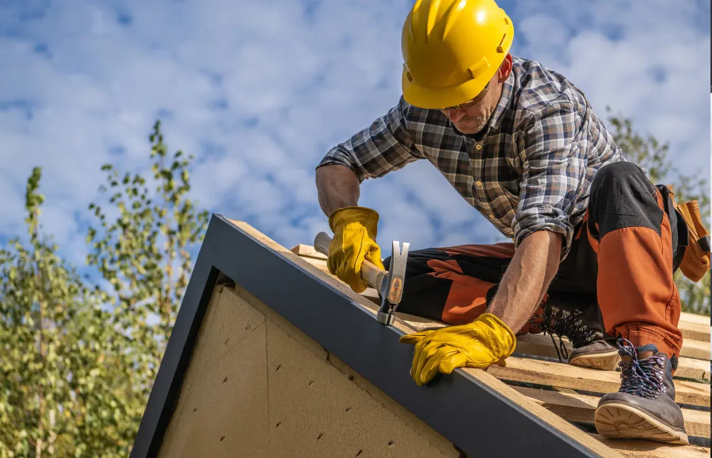 Roofer working on top of roof with hammer